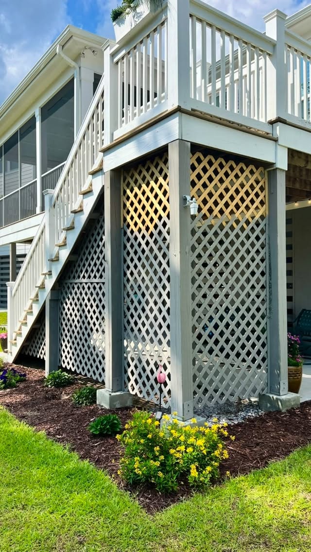 Lattice deck skirt with yellow lantana and tidy mulched beds — Sullivan's Island.
