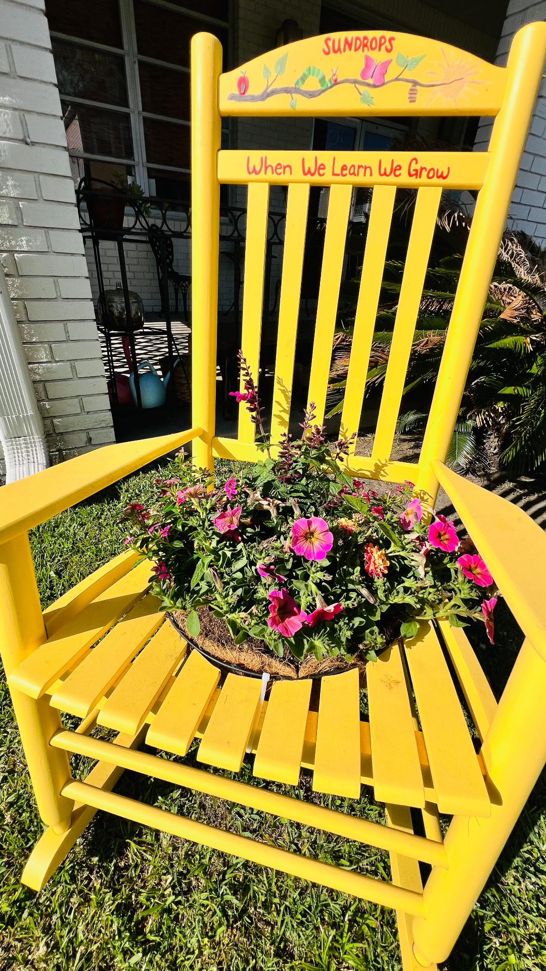 Hand-painted 'Sundrops' rocker overflowing with hot-pink petunias and salvia — Charleston front porch.